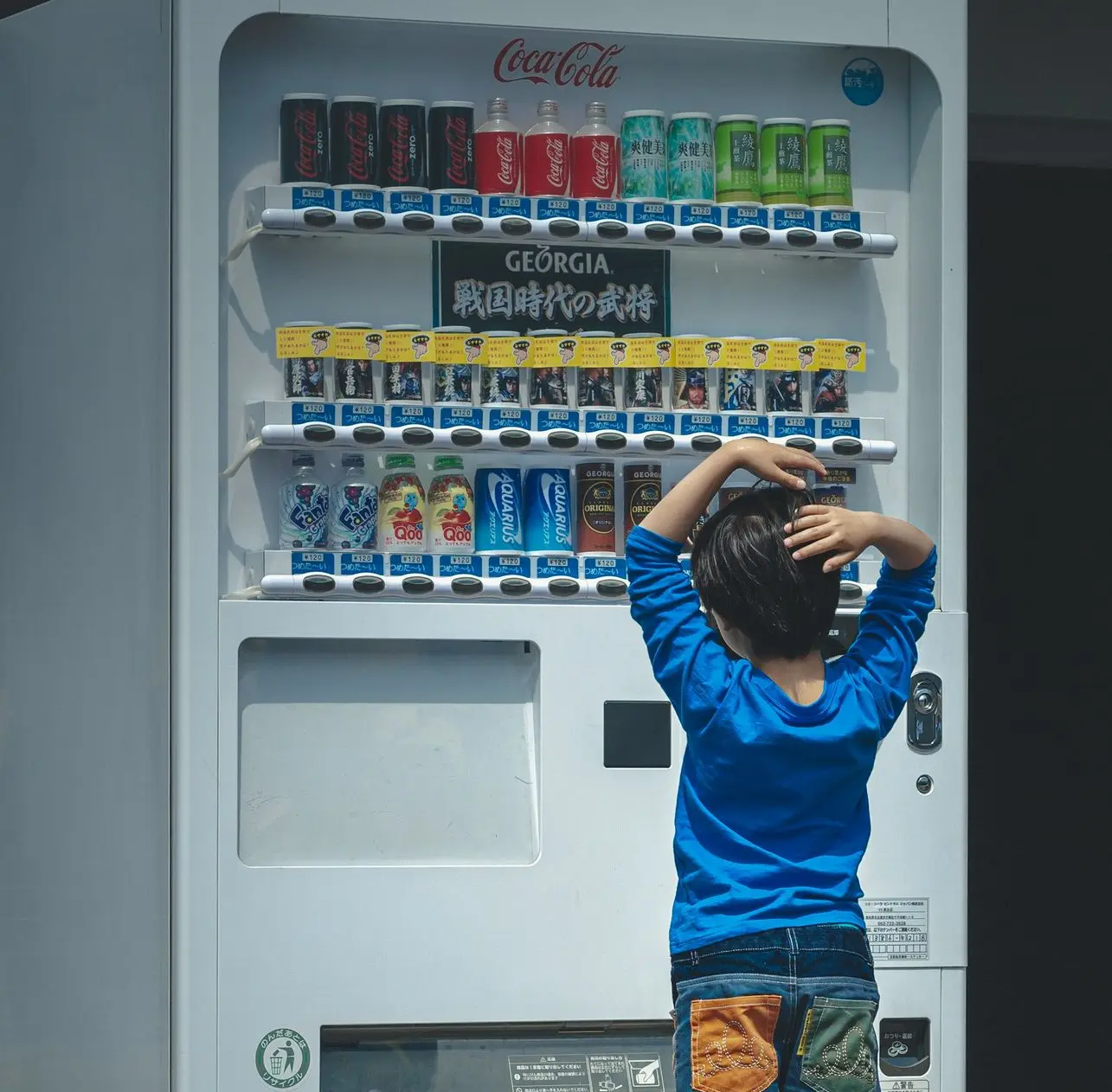 a young boy standing in front of a vending machine